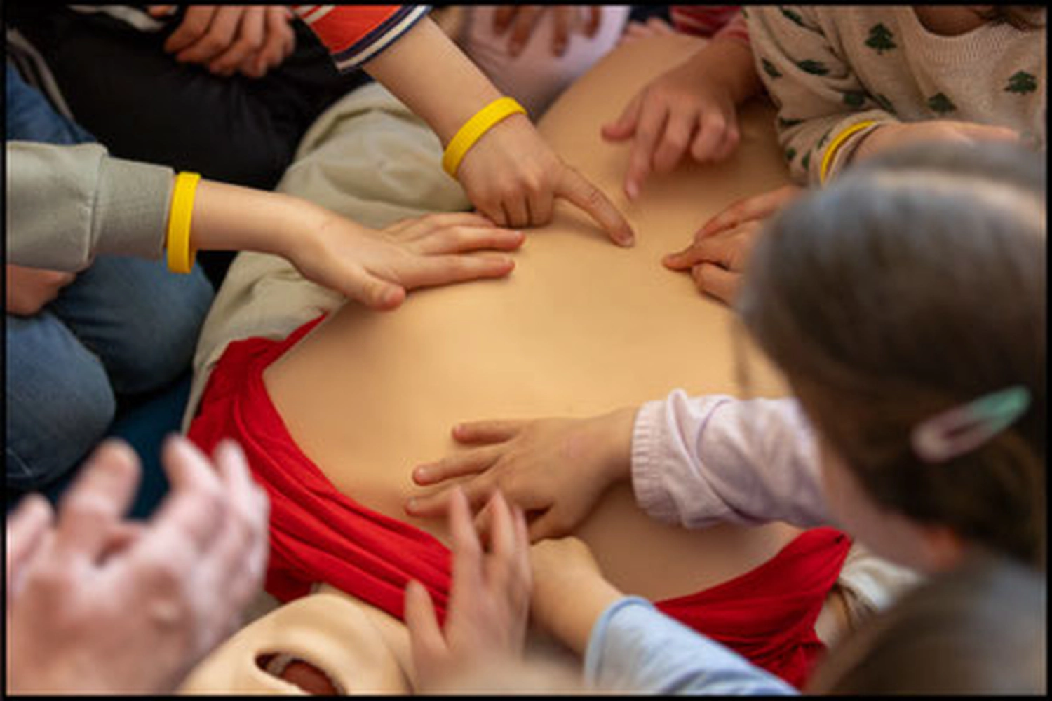 Team Herzdruck – Notfallworkshops – Dieses Bild zeigt eine praktische HLW-Übung, wahrscheinlich für Kinder, mit einer Simulationspuppe.