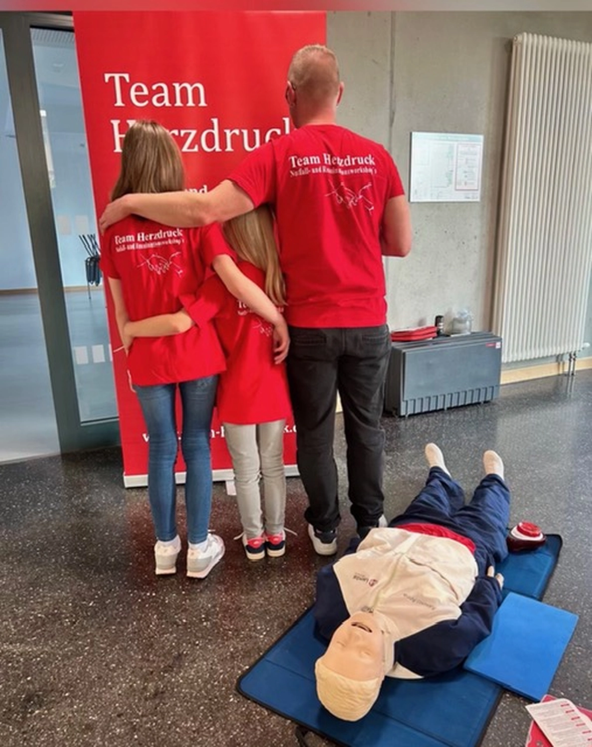Team Herzdruck – Notfallworkshops – Dieses Bild zeigt eine Familienschulung zur Herz-Lungen-Wiederbelebung (HLW) und zur Anwendung eines AED.